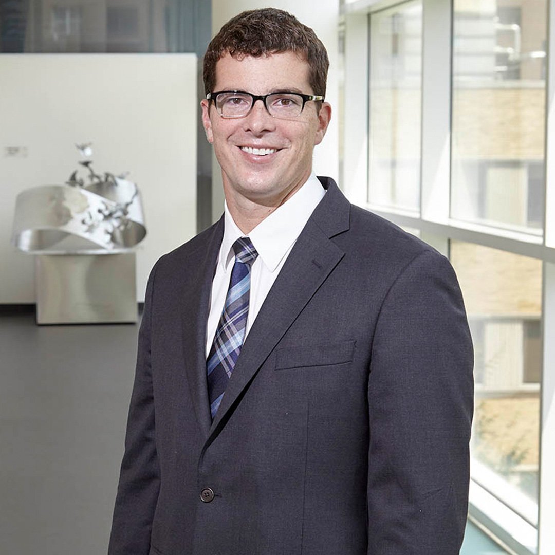 Robbie Moon stands in the Scheller College of Business in a suit and tie