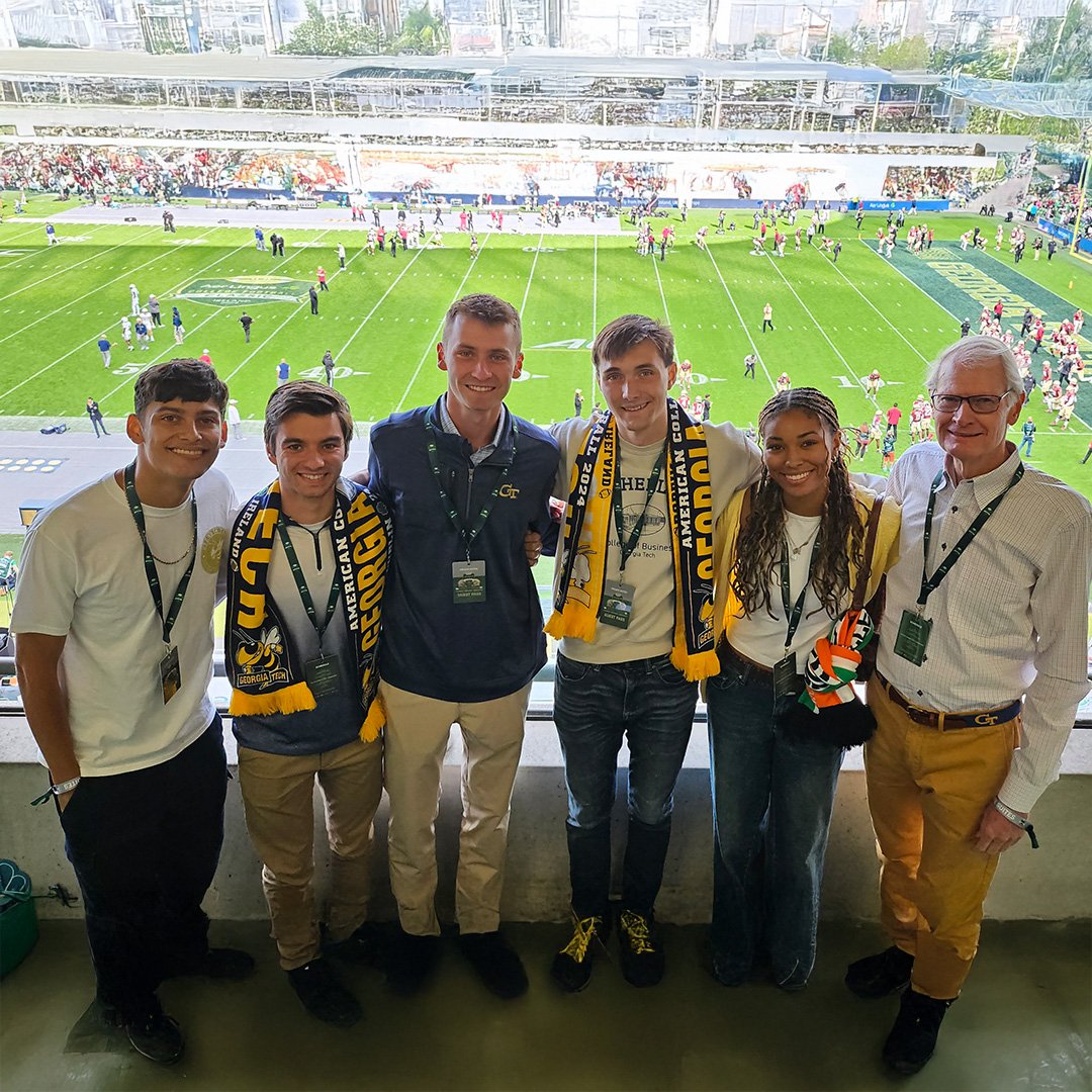  A group of Georgia Tech students and Dick Bergmark stand in front of a football field