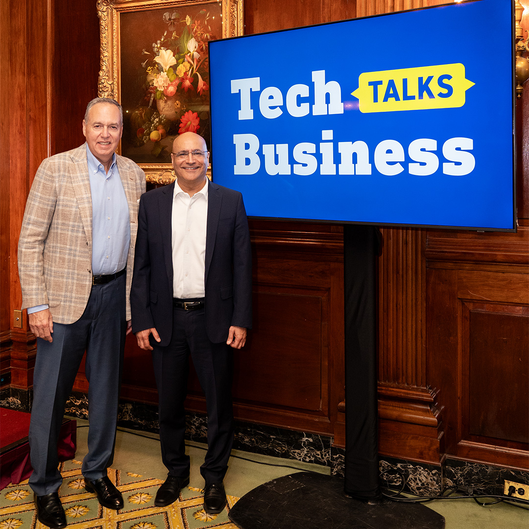 Stephen J. Squeri, Chairman and CEO of American Express stands with Dean Anuj Mehrotra by a “Tech Talks Business” sign
