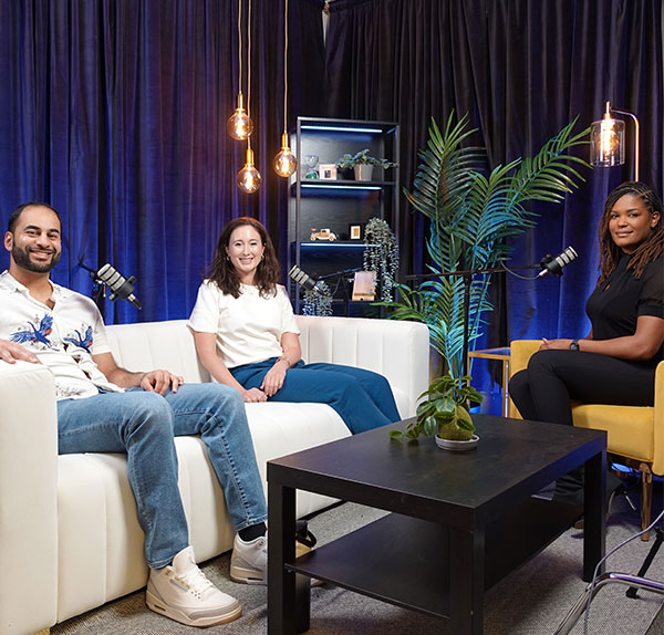 Three people sitting around microphones in a room