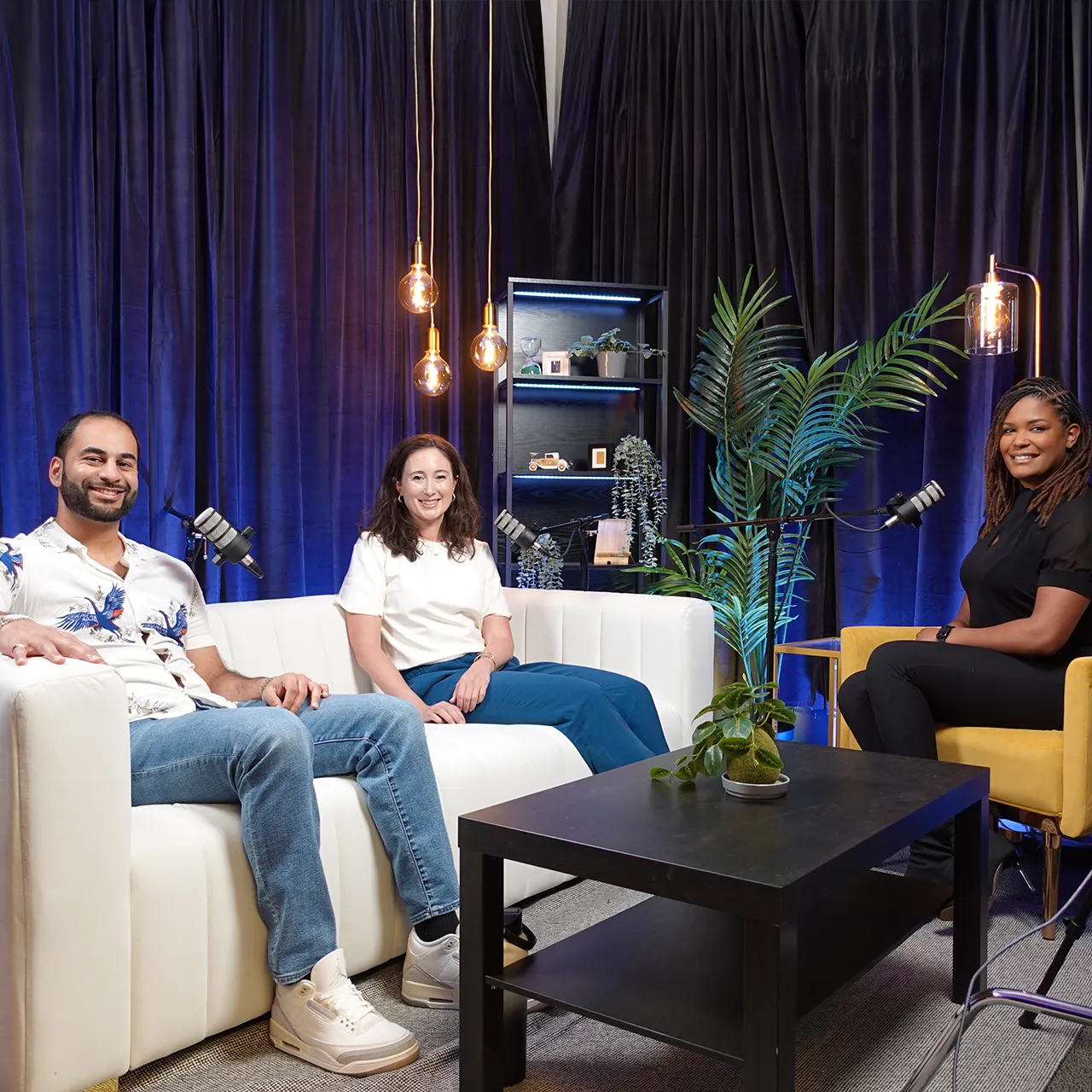Three people sitting around microphones in a room