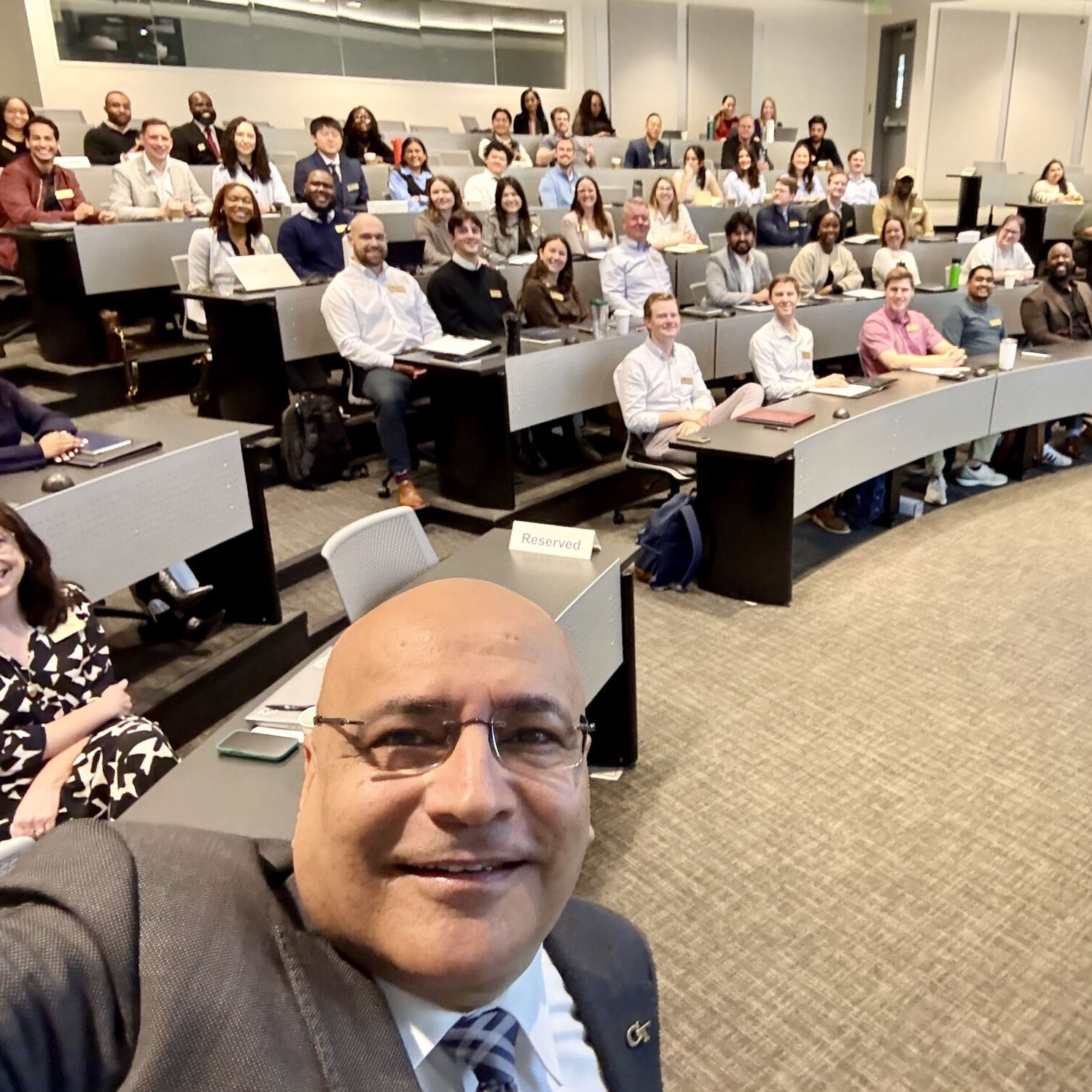 Anuj Mehrotra takes a selfie in a classroom with the new Spring 2026 Evening MBA admitted students during their orientation