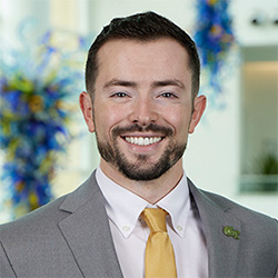 Ryan Dwyer smiles wearing a suit jacket and tie