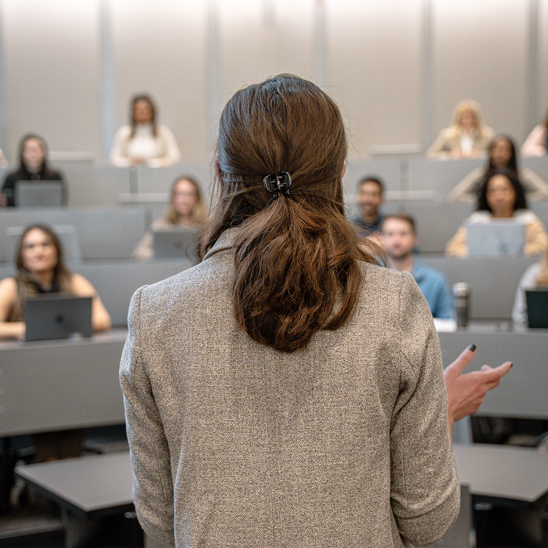 A female instructor stands in front of a Scheller classroom.