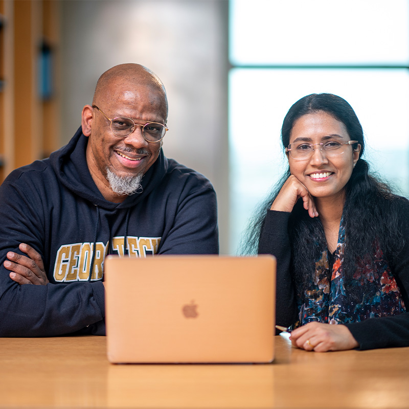 Two Georgia Tech students sitting down next to a laptop. 