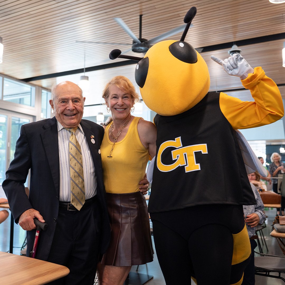 Ernie Scheller Jr. and his daughter, Lisa Jane Scheller, celebrate the ribbon-cutting of the new George Tower | Scheller Tower with Buzz the mascot.