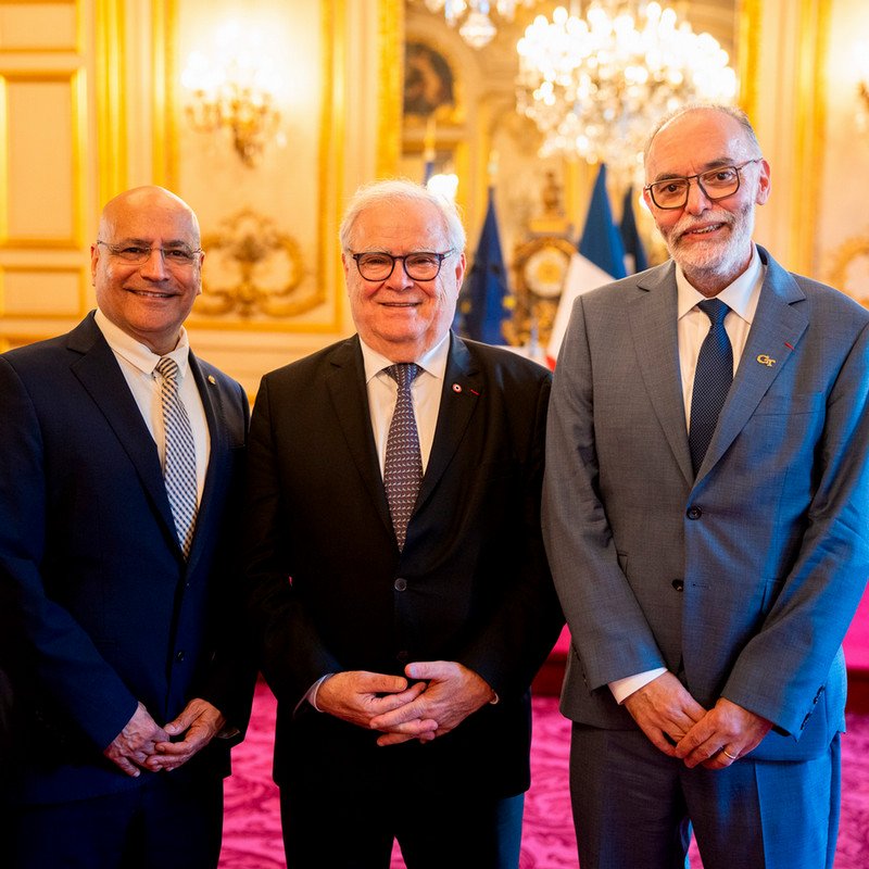 Three men in suits stand together in an ornate reception room at the 2026 Tech Talks Business in Paris event.