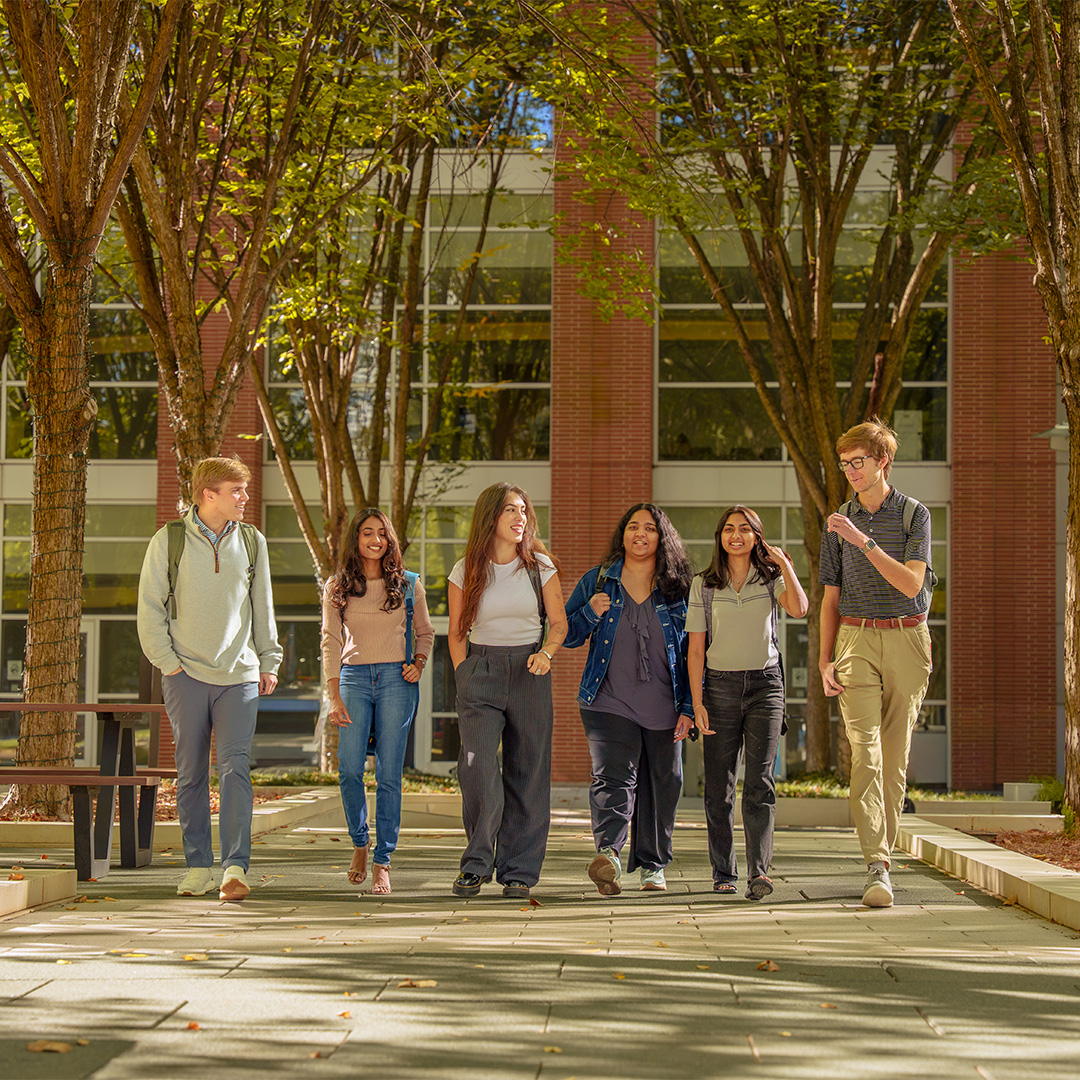 A group of male and female M.S. Major in Management students walk in front of the Scheller College of Business.
