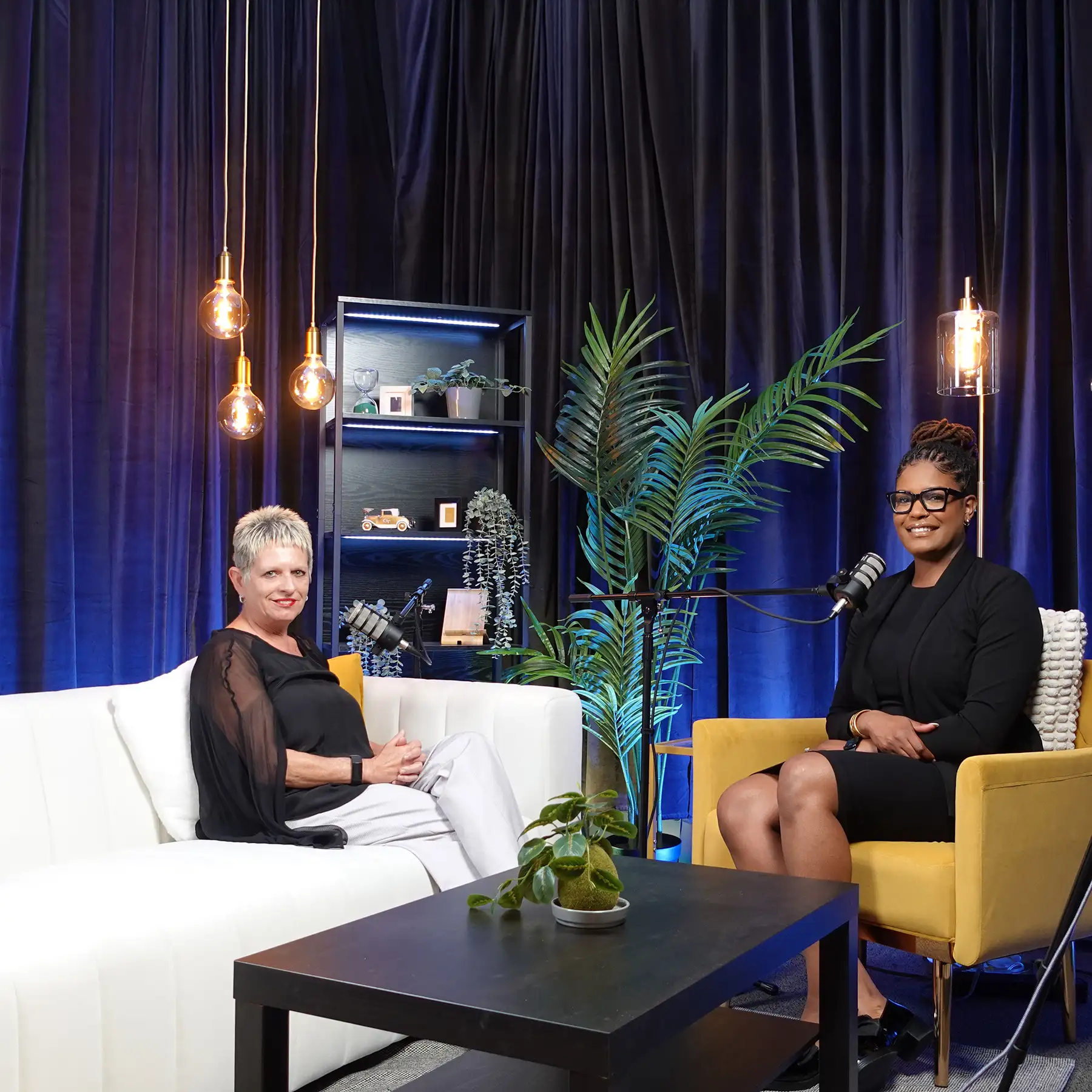 Two women sitting down to record a podcast episode.