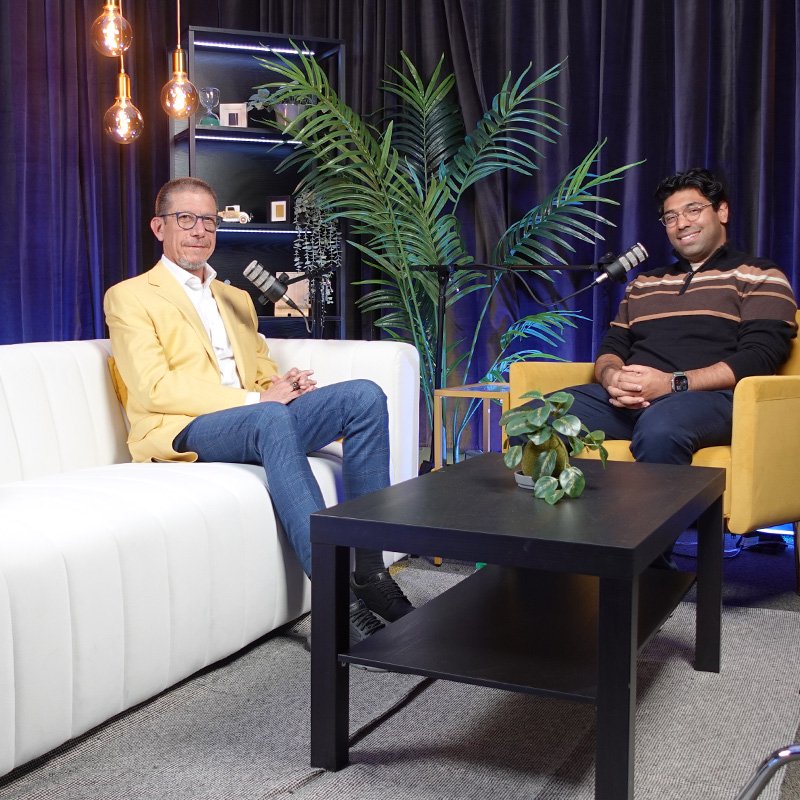 A man and a woman sitting down to record a podcast episode.