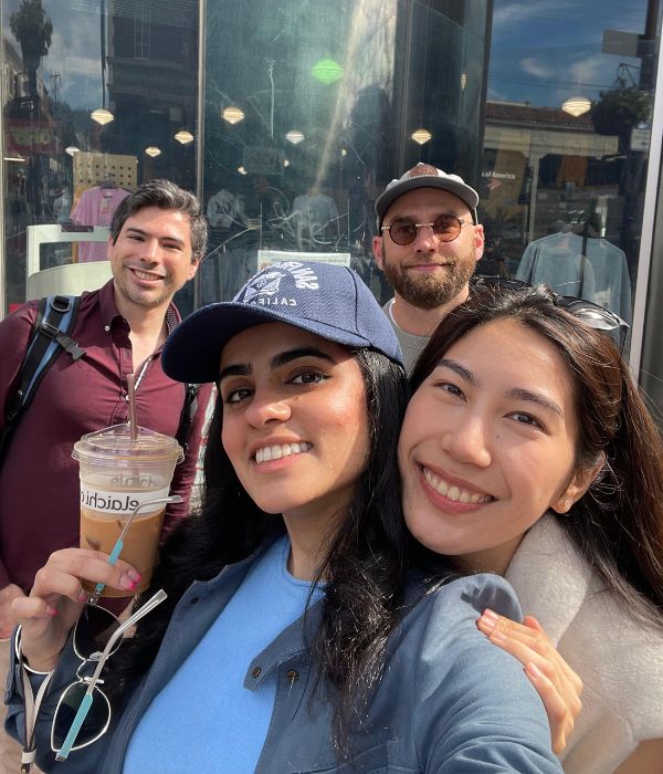 Simar Badwal holding a coffee outside with a group of people
